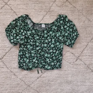 Grön blommig blus/topp - Denna fina blus/topp säljer jag för att jag har tyvärr vuxit ur den. Den är i gott skick och har bara andvänds några gånger.