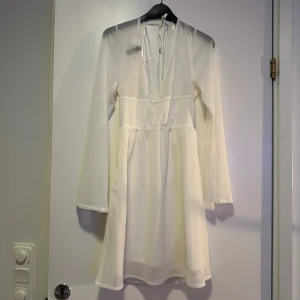 Vit oanvänd klänning - Strl XS men jag som är S kan ha den. Öppen i ryggen med fina knytningar. Endast prövad. Något genomskinlig upptill men dubbla kjol lager. Nypris ca 300