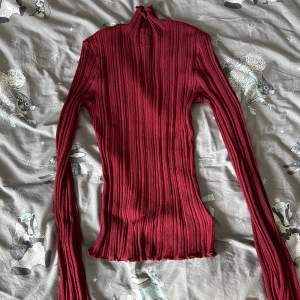 En vinröd tröja från H&M som man ser egendom lite på. I ärmarna så är den utsvängd. 