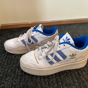 Addidas sneakers - Vita addidas sneakers med blåa detaljer (FORUM BONEGA)💓Säljer då jag har andra skor jag använder mer! Kom privat för bilder💞Nypris: 1 195kr. Priset är 100 kr då jag har använt de ganska flitigt❤️