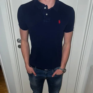 Ralph Laurent Piké marinblå  - Storlek M, men den sitter som storlek S - Skick = 7/10 - Nypris ligger: på 1399kr - Vårat pris: 399kr - Modellen är cirka 180cm och väger runt 66kg.