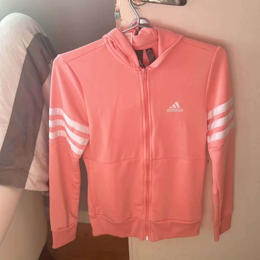 En rosa Adidas tröja i mer sportigt material i storlek 13-14 år (xs). Är i nytt skick och är använd 2-4 gånger . Hoodies.