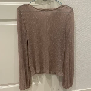 Glittrig topp - Smått genomskinlig glittrig topp. Ganska lång i armarna.