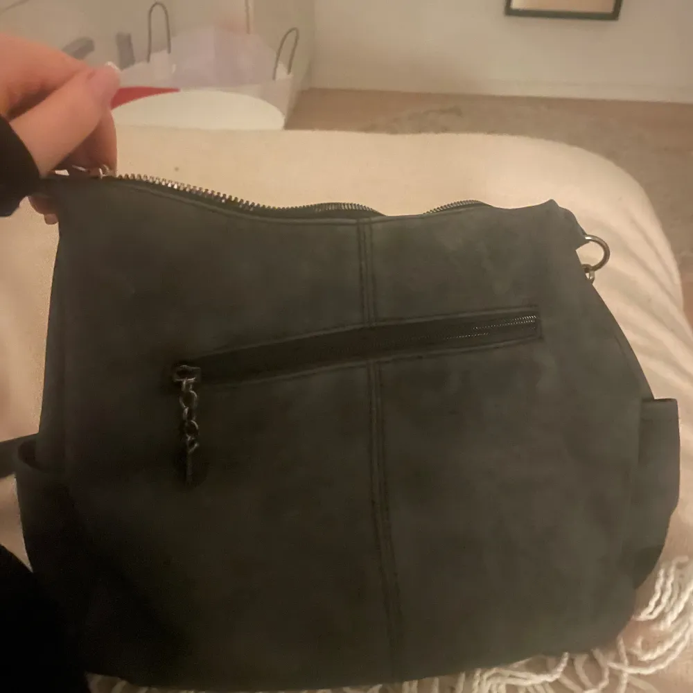 Säljer denna fina gråa väska som är perfekt till skolan/annat då man får plats med hyfsat mycket. Den har två fickor på framsidan och sen en ficka på baksidan. Den är knappt använd💓. Väskor.