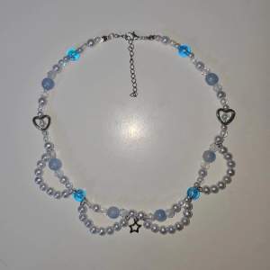 Handgjort halsband av mig i blått och vitt. Halsbandet är gjort med mesta dels plast pärlor men också några glas pärlor. 