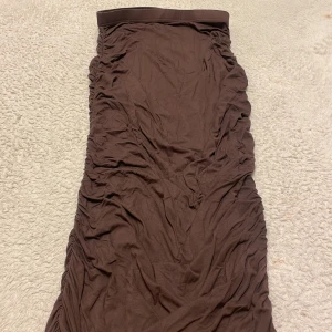 Brun kjol  - En lång brun fin kjol. Kjolen sitter sååå himla snygg och perfekt på. På sidorna har den en remsa som drar åt lite så att den sitter som ett smek💕har aldirg hunnit använda den tyväär 