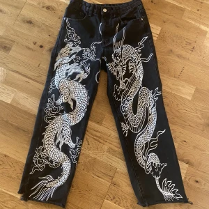 Coola jeans med tryck - Ett par svarta coola baggy jeans med vitt tryck. Använda några gånger men ändå jättebra skick, lite slitna längst nere men det är inget man märker❤️