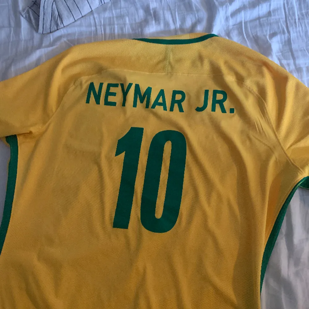 Fet brasilien tröja med neymar på ryggen! Perfekt till sommaren och 100% authentic! Tyvärr har nikeloggan börjat släppa lite men går nog lätt att limma! Storlek XL men sitter som L!. T-shirts.