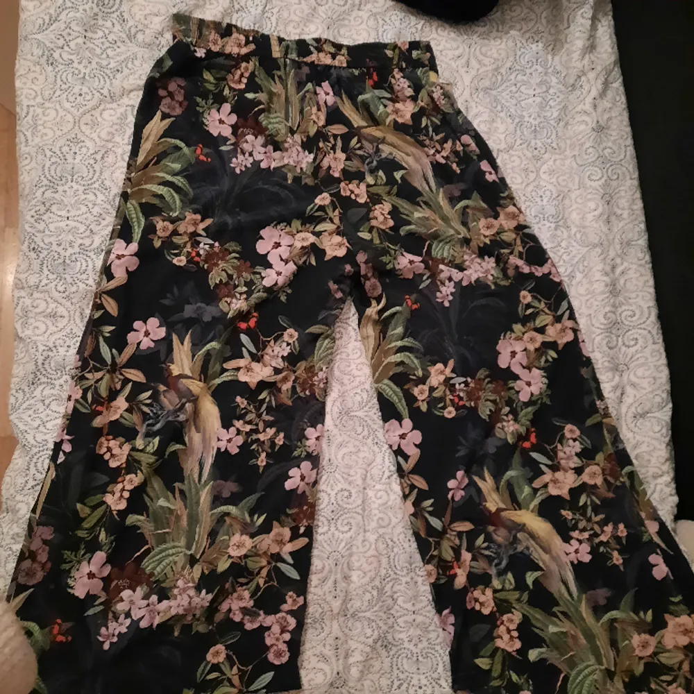 Somriga svarta byxor med blommprint<3 mjukt tyg, breda byxben. Storlek L (lita inte på bilden de passar inte mig, ville ba visa hur de faller). Secondhand men bra skick:). Jeans & Byxor.