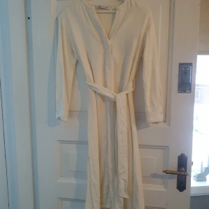 Linne klänning  - Klänning i linne med fint, tungt fall. Sprund i sidorna och band i midjan. Mer naturvit än vit.