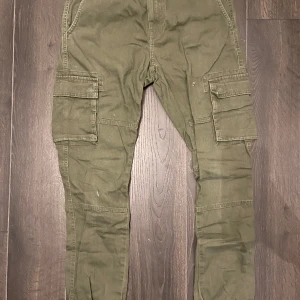 Gröna cargobyxor - Gröna cargobyxor i storlek 30/34. Har enstaka hål i byxorna annars bra skick! Tveka ej med att ställa frågor.