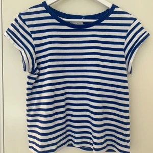 En blå randig T-shirt - Köparen står för frakten. Säljer denna randiga tröja för att den inte passar. Denna är väldigt fin tills sommaren och har använts ett par gånger. 