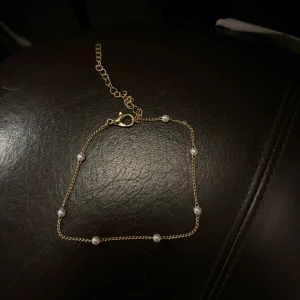 Guldfärgat armband  - Ett jätte fint guldfärgat armband med mindre vita pärlor. Använd några gånger men är i toppenskick! 