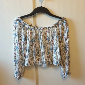 Blommig top - En off shoulder crop top med blommigt motiv. Använd ett par gånger men är fortfarande i väldigt bra skick! Ganska liten i storleken så skulle säga att den sitter mer som en XS.