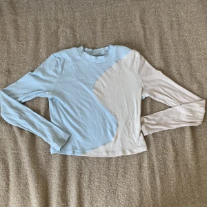 Ljusblå och vit långärmad tröja från H&M - En långärmad tröja från H&M i ljusblått och vitt. Tröjan har ett unikt mönster med båda färgerna och är ribbad i materialet.