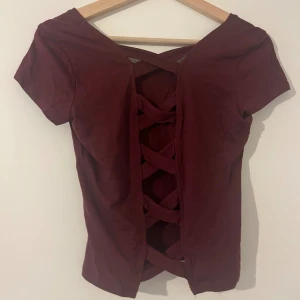 Vinröd ropp med detalj - Vinröd topp med snygg detalj i ryggen. Storlek L, men funkar också som M. Knappt använd.