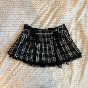 rutig minikjol - Svartvit rutig kjol med rosettdetalj från Currentmood. Strl M, aldrig använd!