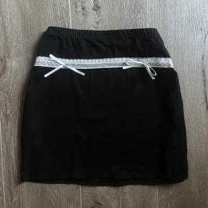 Fin svart kjol 🖤🤍 - Fin svart kjol med vit spets och rosett detalj. Bra skick, aldrig använd. 🩷