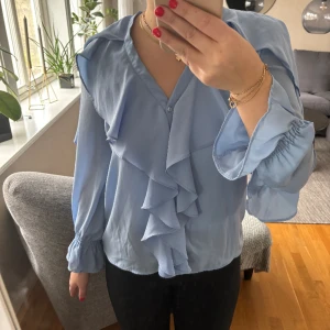 Volangblus  - Blå blus från zara, har ett hål på armen men är lagat med en säkerhetsnål på insidan ( se bild 3) 