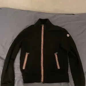 Moncler fullzip. Riktigt trendig med feta detaljer. Den har en liten söm som har gått upp på höger ficka men inget man märker. Priset är ej hugget i sten!!!