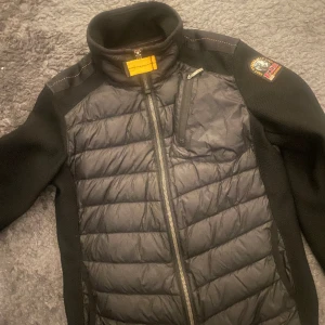 Parajumper jacka  - 2 pytte pytte små hål. Lätt laga med nål och tråd. 