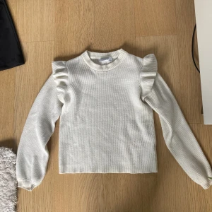 Stickad vit tröja, med volangärm - Säljer denna vita stickade tröja. Använd fåtal gånger under hösten och är i fint skick. Från början köpt från vila.💗