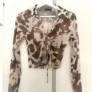 Meshtopp med koskinnsmönster - Mesh tröja med knytning, krage och koskinnsmönster! Bra skick! Storlek S, 36.