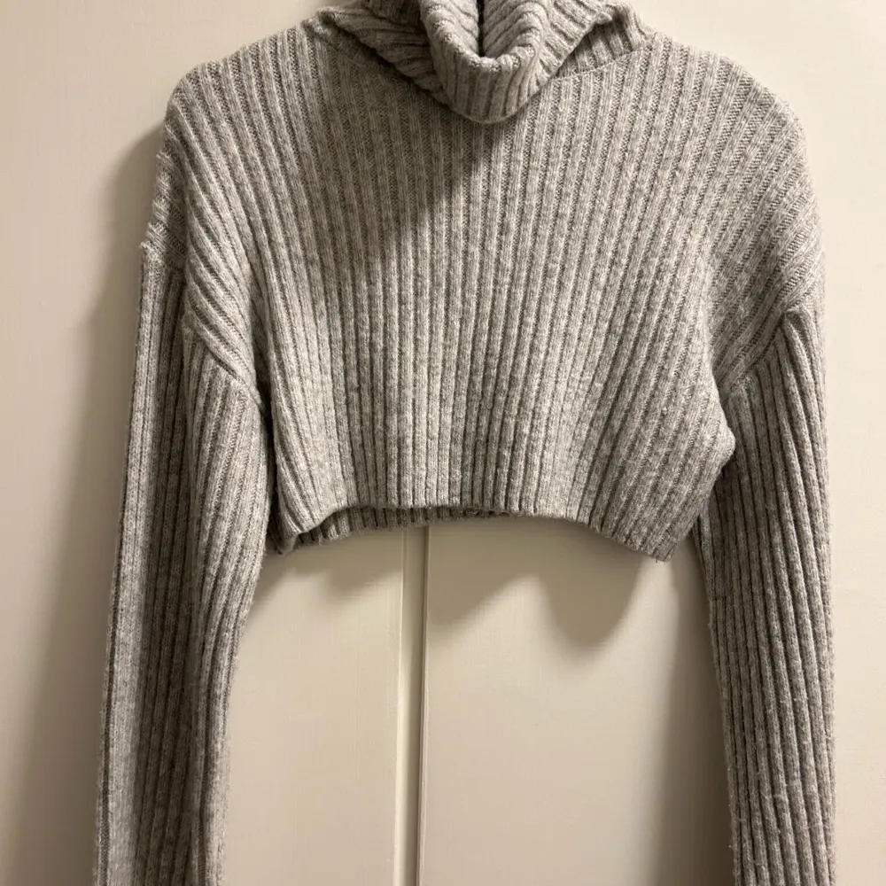 Säljer denna fina croppade stickade tröjan i färgen grå, då den inte kommer till någon nytta. Använd 2 till 3 gånger!. Stickat.