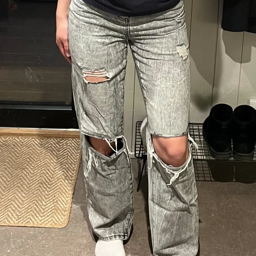 Ett par gråa jeans i storlek 36. Modellen på dessa är straight. Skulle säga att de är ganska high-waist. Även dessa har hål vid knäna som ger en lite street-ig look. Ganska väl använda men i bra skick. Litet hål mellan benen, men syns ej när de är på. Jeans & Byxor.
