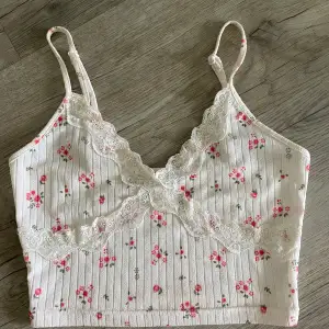 Ett vit/rosa linne med blommor på, kortare i modellen. 