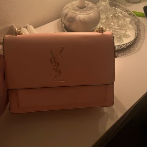ysl väska - väldigt söt ysl väska, den är inte äkta men kosta runt 300-500 kr. finns 3 fack i den och är kedjan i guld. ☺️