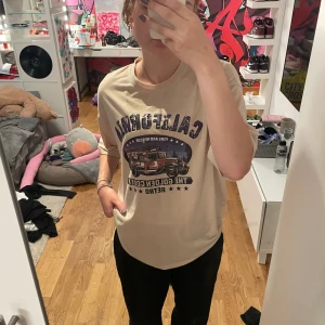 T shirt  - Säljer en beige t shirt med tryck av bl.a en bil. Säljer då den inte är min stil längre och har legat oanvänd i min garderob i över ett år 