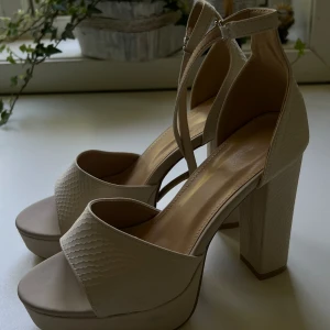 Beige klackskor - Beige klackskor. Storlek 38. Aldrig använda. Liten skada på höger yttersida, syns på bild 2. 