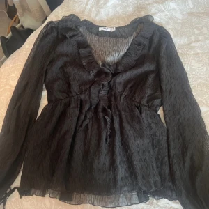 Svart blus  - blus i svart från na-kd med v-hals och volangdetalj. Köpt nyligen, endast testad. 