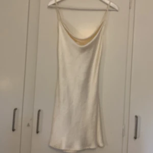 Minislipdress m öppenrygg och knytning  - Vit satinklänning med öppenrygg från motelrocks! Knytningen är justerbar, man knyter som man vill ha det Använd typ 2-3 gånger  Perfekt skick