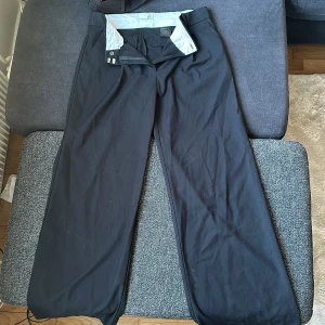 Finbyxor wide leg  - Ett par vida finbyxor med kedja och metalk appar. Lår 31 cm. Midja 39 cm. Längd 100 cm. 