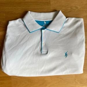 Ralph Lauren Piké - En vit Polo Ralph Lauren pikétröja med blå design på kragen | Storlek XL | Mycket fint skick 👍    Modellen är 182cm lång, väger 75kg  Kolla in min profil för fler pikétröjor, skjortor och annat till bra pris! Fler varor kommer inom kort 💸