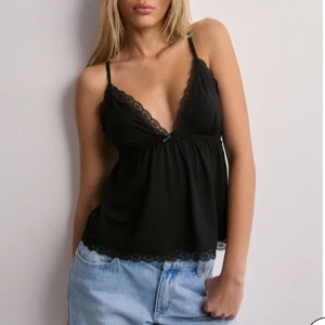 Svart linne med spets Nelly - Säljer ett jättesött linne med spets från Nelly. Aldrig blivit använt då jag inte tyckte jag passade i plagget. Har kvar prislapp på tröjan o allt:)  Original pris på nellys hemsida är 250 kr🩷 