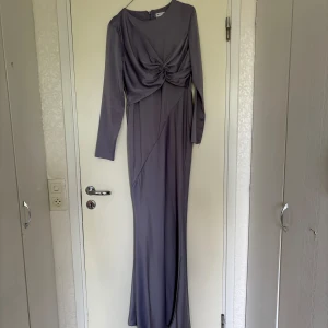 Långklänning från ASOS DESIGN - En elegant långklänning från ASOS DESIGN i en ljuslila färg. Klänningen har långa ärmar och en knutdetalj framtill som ger en smickrande passform. Tillverkad i ett mjukt och följsamt material.