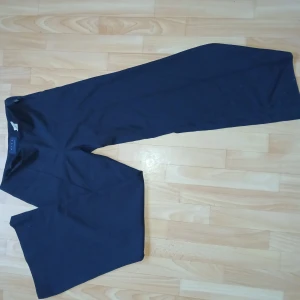 Svarta byxor från Dico Copenhagen - Ett par vida svarta byxor från Dico Copenhagen i 45% ull. Byxorna har en enkel design med sömlinje längs låren och är tillverkade i ett mjukt och bekvämt material. Väldigt utsvängda ner till.