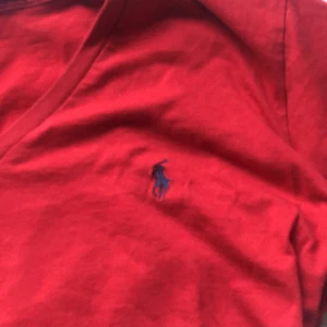 Röd Ralph lauren t-shirt - Supergullig röd Ralph lauren t-short med v-ringning. Skulle säga att T-shirten mer är en S än en M.