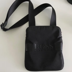 HUGO BOSS - Axelremsväska - Säljer en nästan oanvänd, nyinköpt väska. Den är jättefin och har gott om plats. Perfekt för att slippa ha saker i fickorna. Enkel och smidig att använda :)