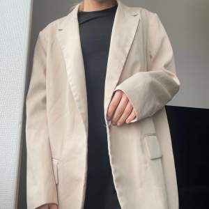 En oversized blazer i beige som jag säljer för att den aldrig kommer till användning. Endast använd en gång.