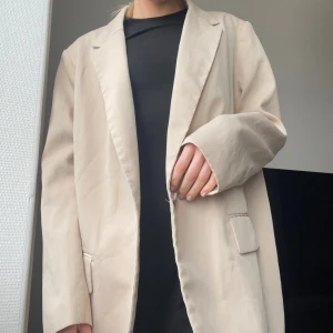 Oversized blazer - En oversized blazer i beige som jag säljer för att den aldrig kommer till användning. Endast använd en gång.