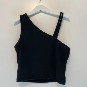 Svart linne  - Ett superfint svart linne med detaljer på ena ärmen. Använda denna topp hela förra sommaren men finns inga defekter eller liknande. Materialet är superstretchigt!! Köpt för 150kr