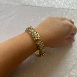 Runt armband  - Guldigt armband, passar både till vardags och fest.  Finns lite slitage på insidan, men inget som syns.