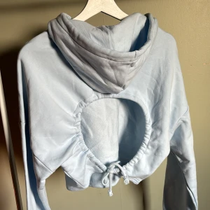 Croppad hoodie med öppen rygg   - Ljusblå croppad hoodie med öppen rygg från Monki i stl S. Mer baby blå i verkligheten än på bild. Aldrig använd. 