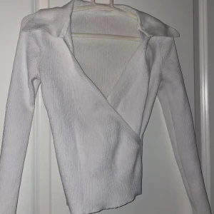 Vit tröja med korsning fram  - Vit Ribbstickad tröja med korsning fram vid bysten. Mycket bra skick. Använd en gång. Storlek S. Är inte säker på vart den är ifrån, men tror chiquelle. 