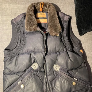 Parajumper väst  - Storlek M.  Använd lite sliten  Dragkedjan fungerar men som man ser på bilden ovanför så har själva ”handtaget” gått av.