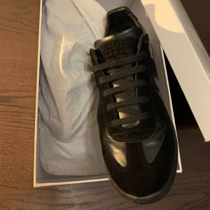 Maison Margiela GAT  - Sjukt snygga all black Maison Margiela GATs i väldigt fint skick, använda fåtal gånger. Självklart äkta och vid köp ingår två originela dustbags och originalbox. Nypris är över 5000 kr och vårat pris är 3199kr😈Har kvitto.  Storlek 41, TTS. 
